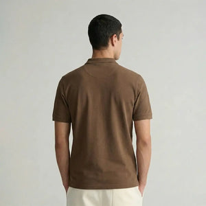 Man wearing a brown polo shirt against a plain background