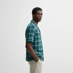 Man wearing a green plaid shirt against a white background