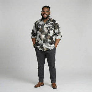 Man wearing a patterned shirt and dark pants on a gray background