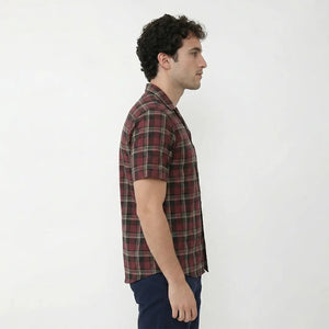 Man wearing a red and black plaid shirt against a white background