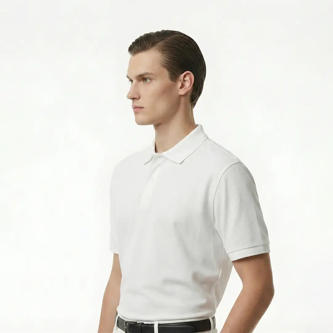 Man wearing a white polo shirt on a plain background