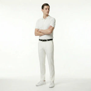 Man wearing a white polo shirt and pants with a black belt on a white background