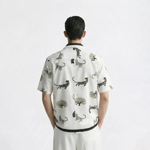 Person wearing a white shirt with black animal prints on a plain background