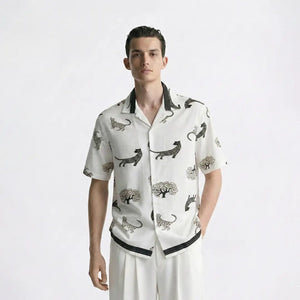 Man wearing a white shirt with black animal prints on a plain background