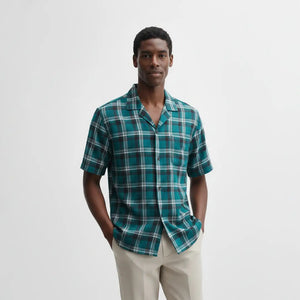 Man wearing a green plaid shirt against a white background