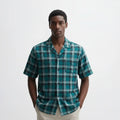 Man wearing a green plaid shirt against a white background