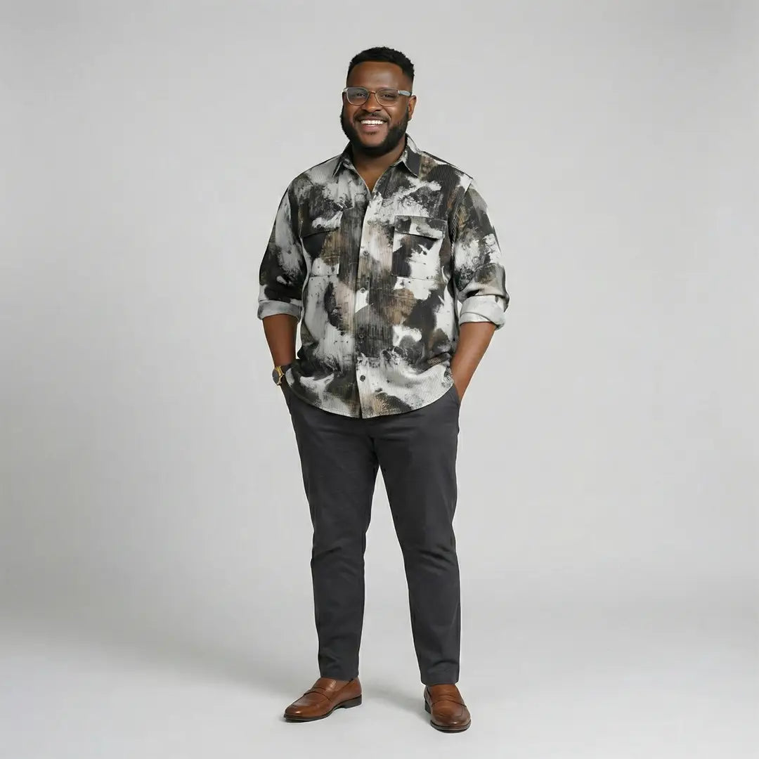 Man wearing a patterned shirt and dark pants on a gray background