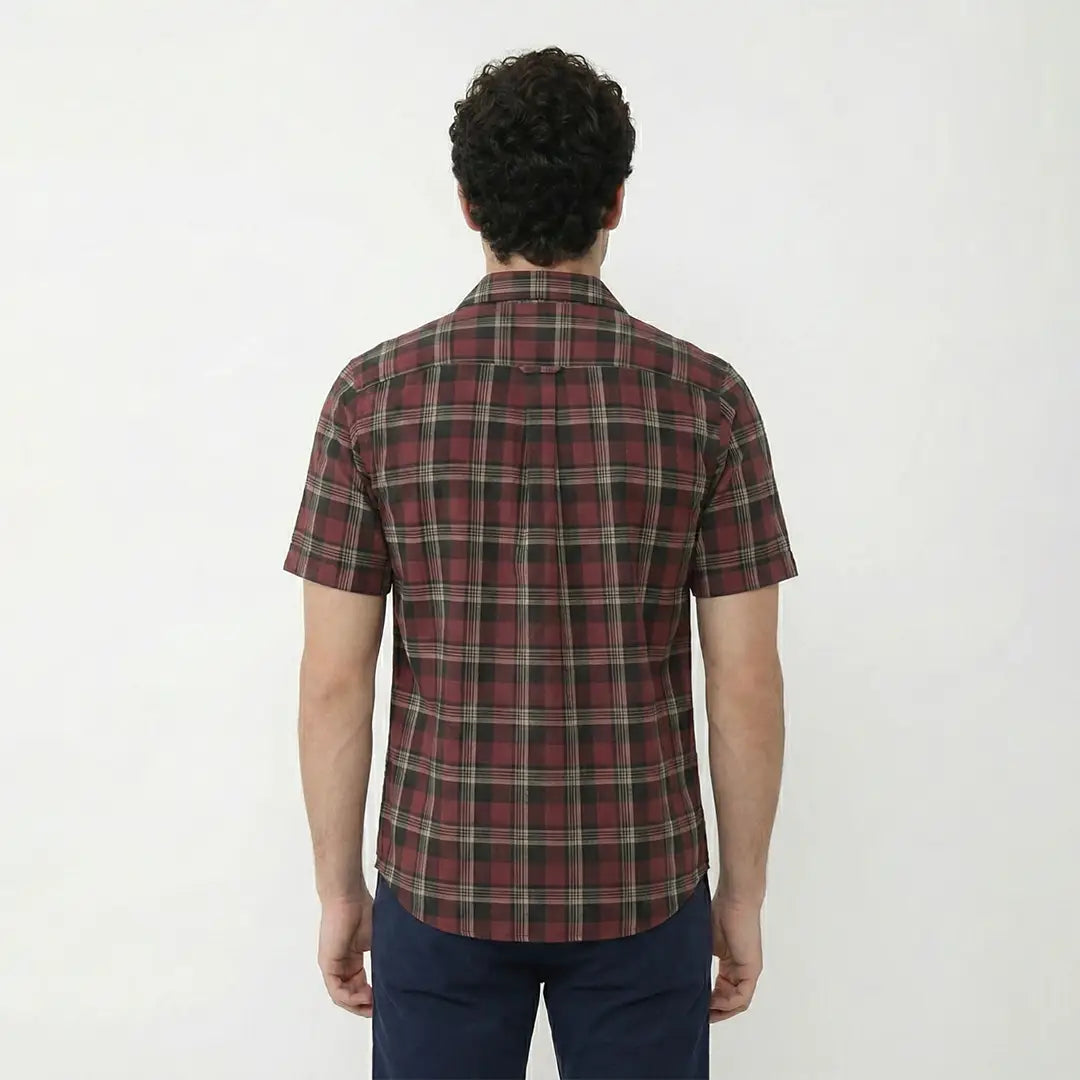 Person wearing a red and green plaid shirt on a white background