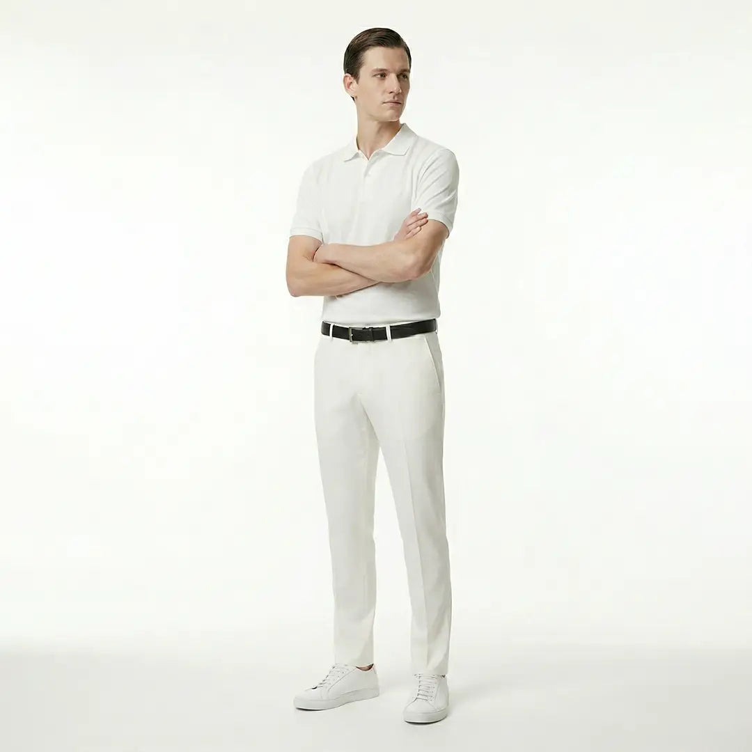 Man wearing a white polo shirt and pants with a black belt on a white background