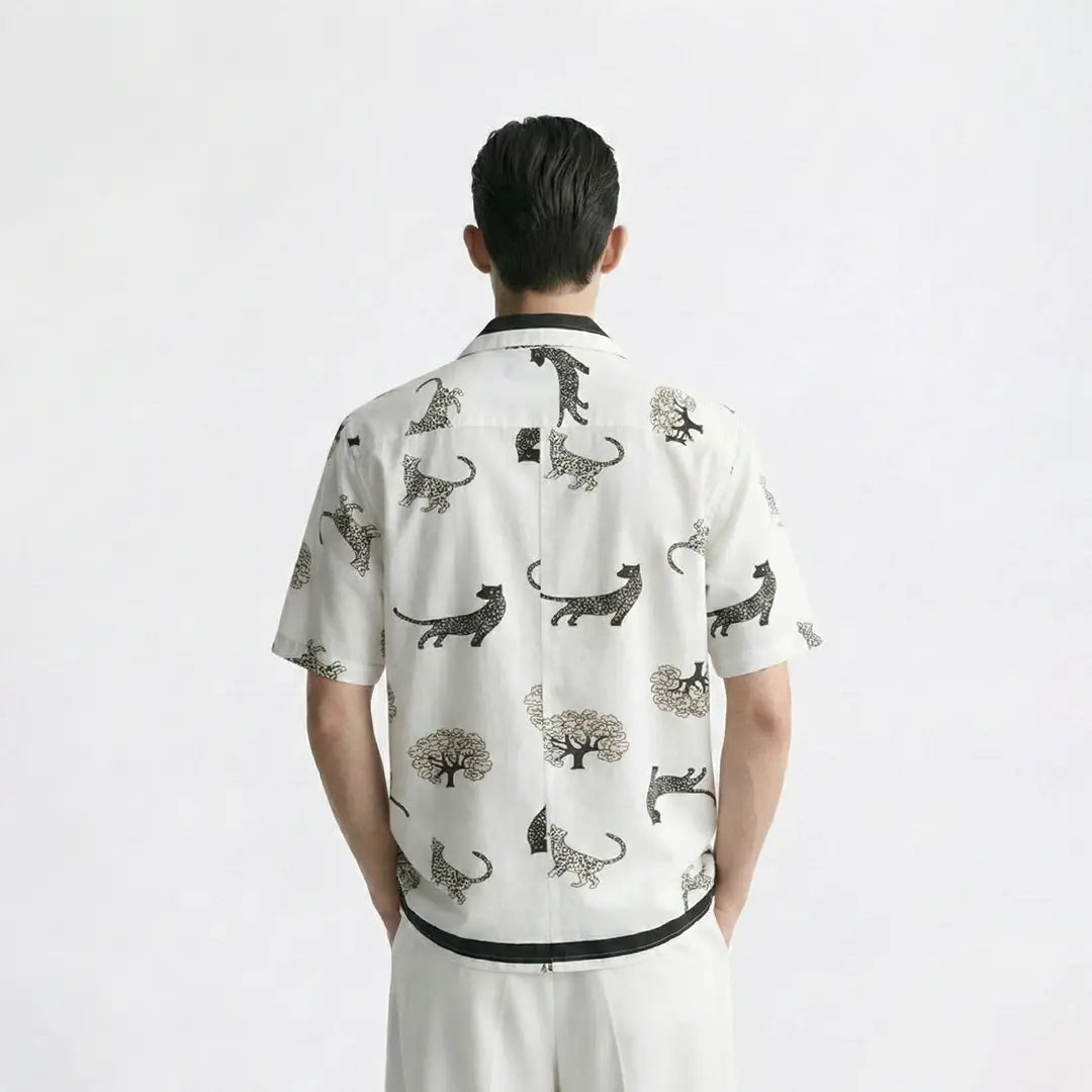 Person wearing a white shirt with black animal prints on a plain background