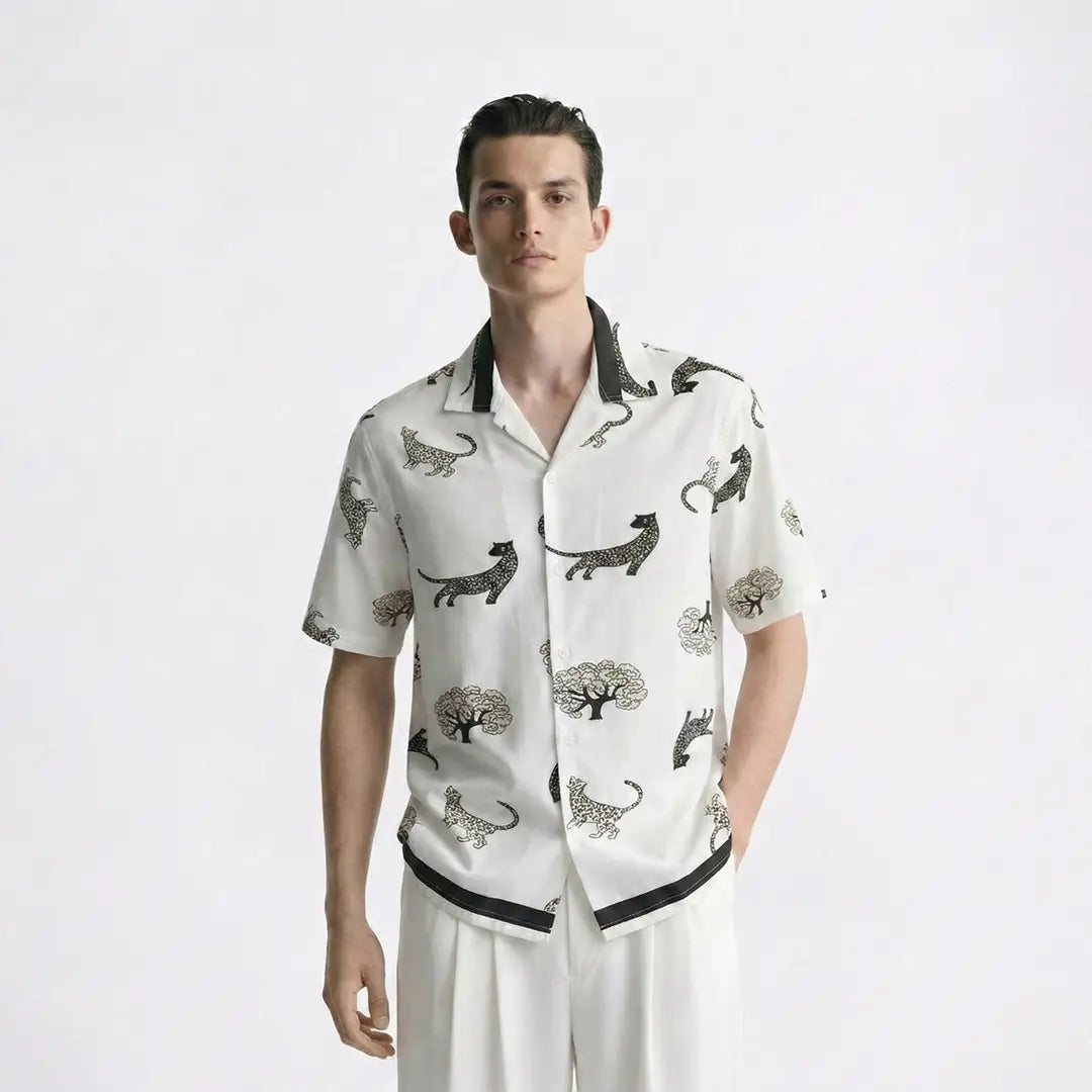 Man wearing a white shirt with black animal prints on a plain background