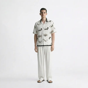 Man wearing a patterned shirt and white pants on a white background